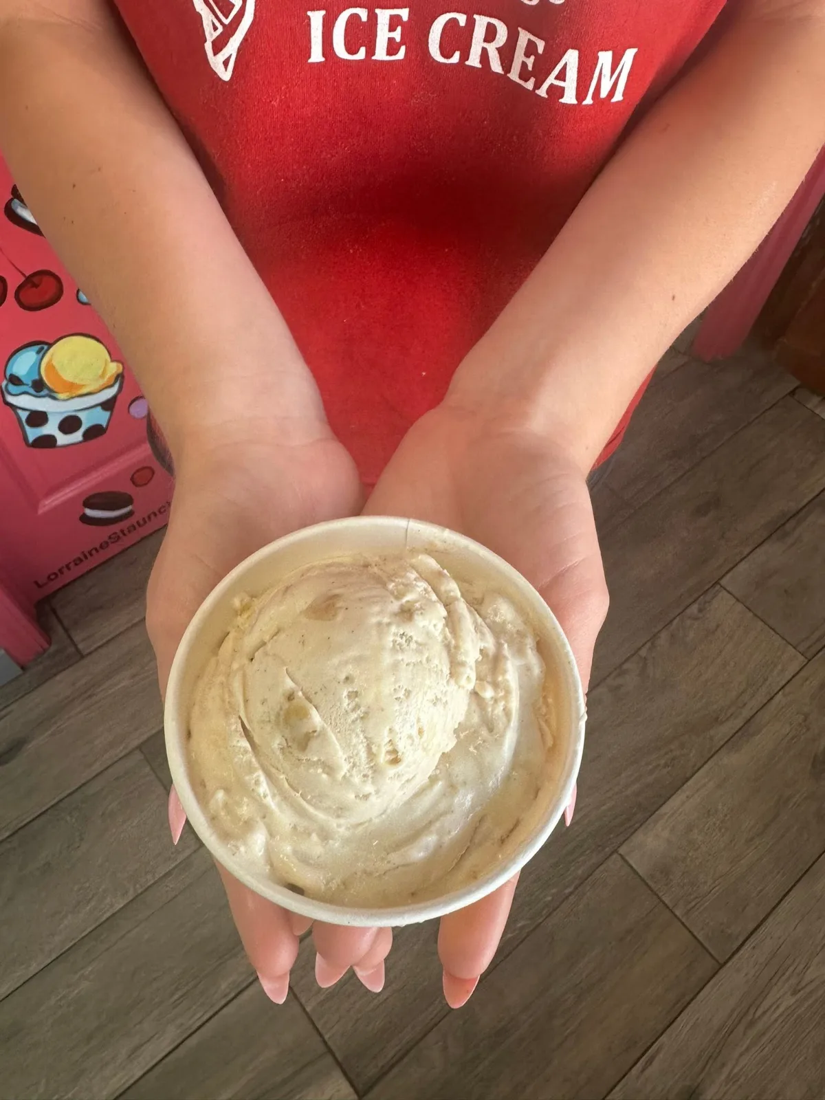 A cup of carrot cake ice cream held out over the counter