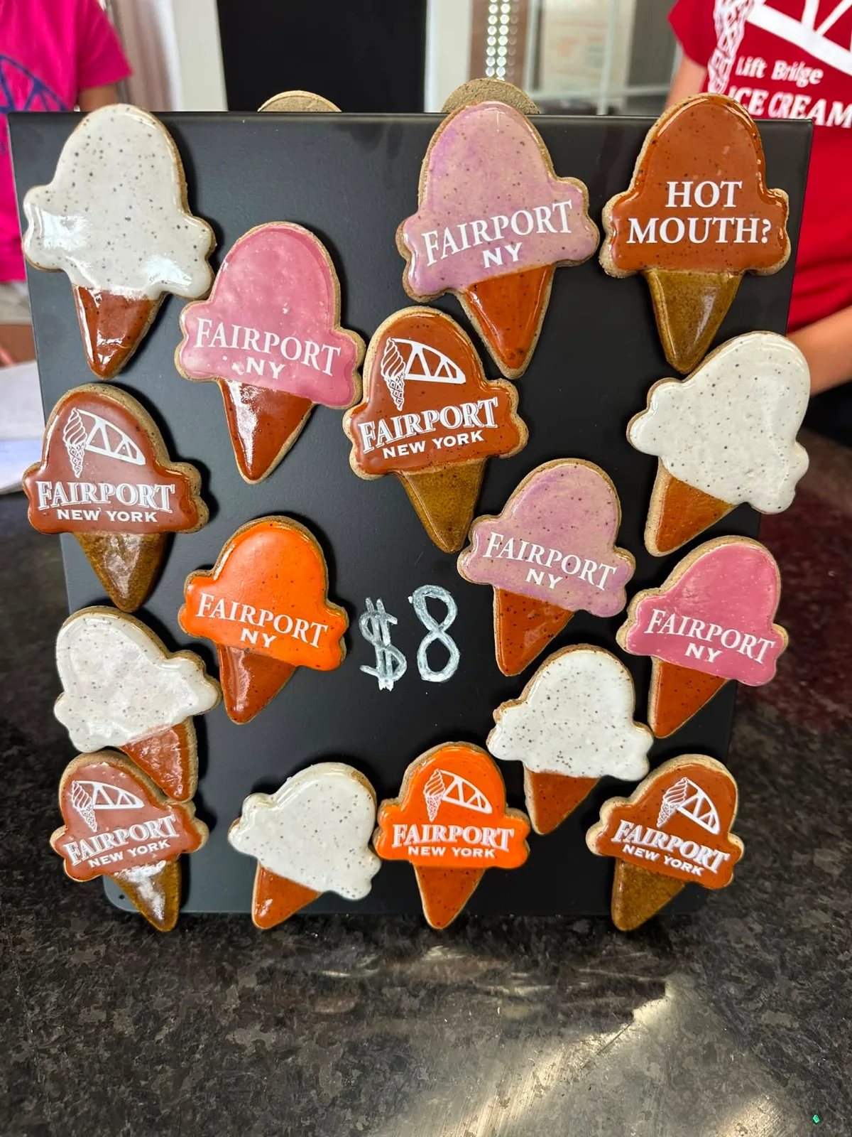 Ice cream cone magnets that say Fairport, New York, on a board by the register